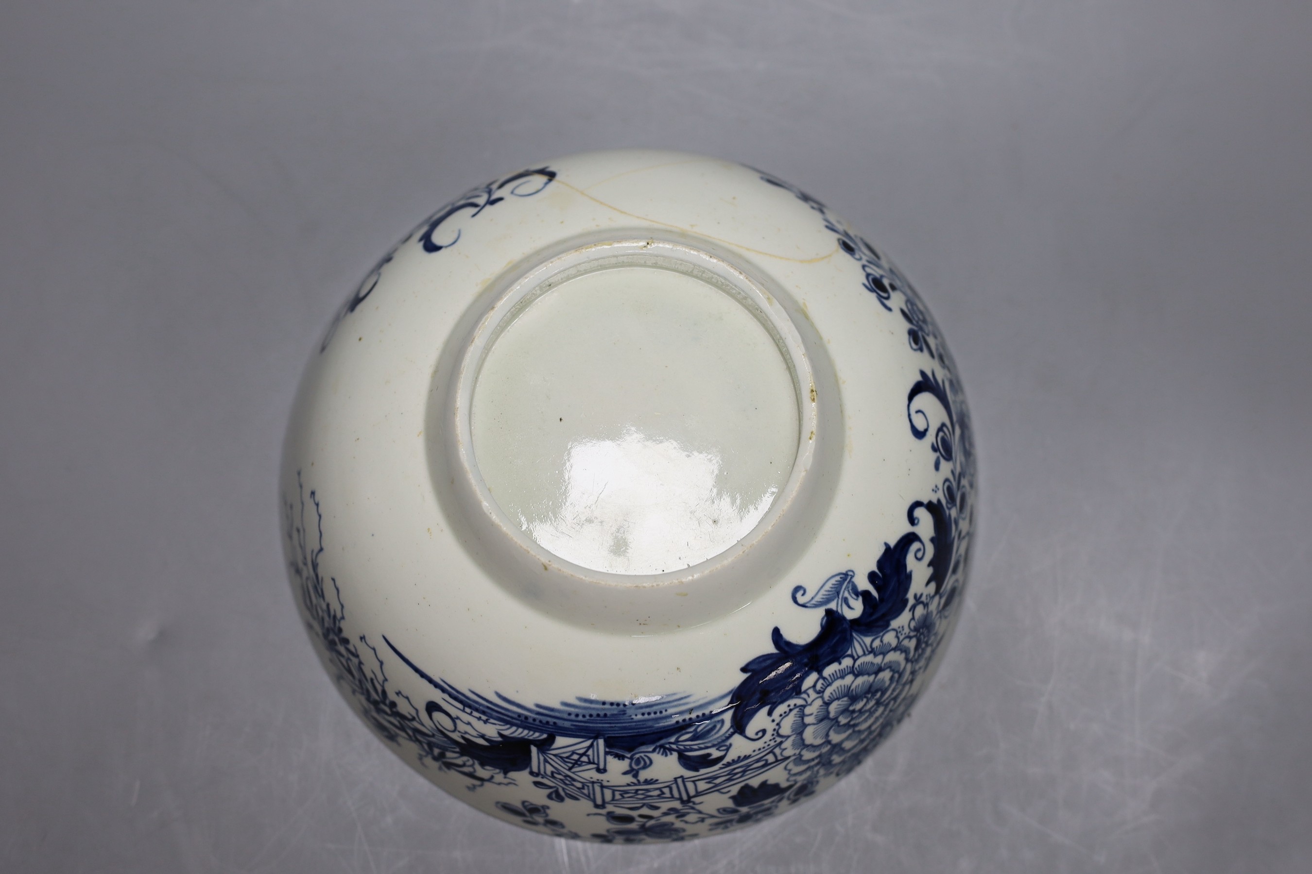 A Liverpool punch bowl, hand painted with flowers and a fence in blue underglaze, 23cm diameter